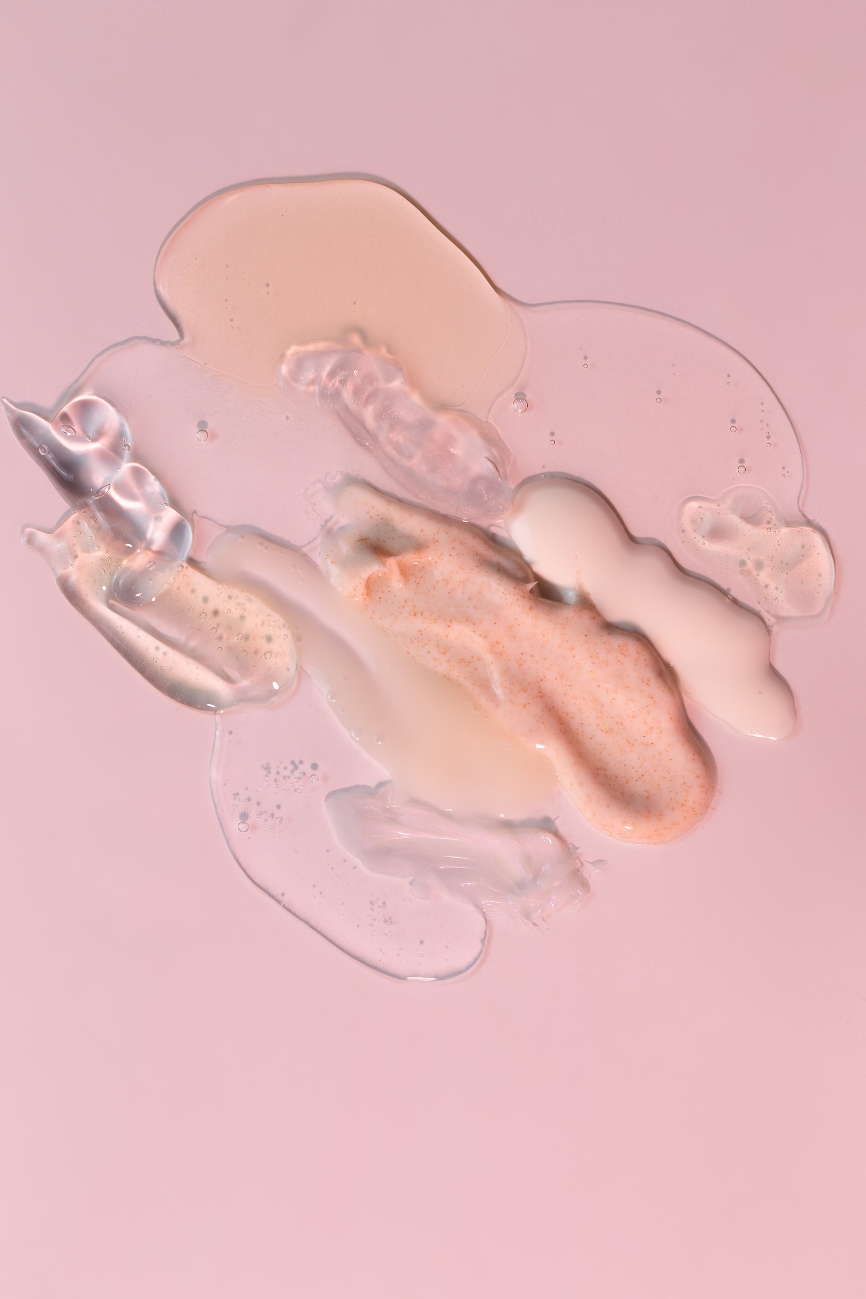Assorted Liquid Skincare Products on Pink Background